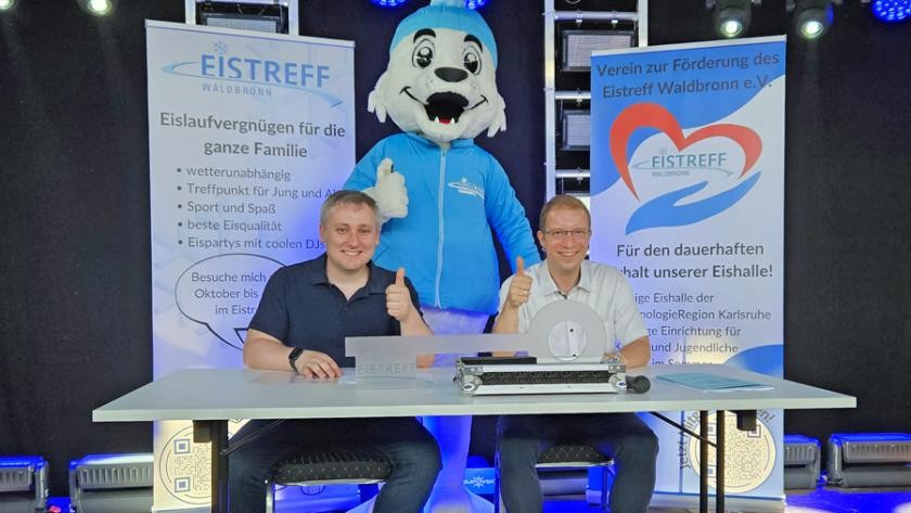 Geschäftsführer Alexander Schroth (links) und Bürgermeister Christian Stalf unterschreiben den neuen Pachtvertrag. Maskottchen Snowy freut sich ebenfalls.